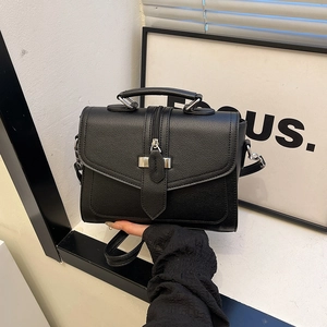 Chic black textured leather handbag with top handle and crossbody strap on white background