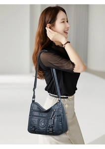 Détail d'un sac à bandoulière en cuir lavé bleu foncé avec multiples fermetures