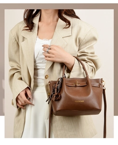 Detail of dark brown leather handbag with gold turn-lock closure and white stitching