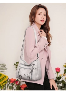 Detail of light grey multi-pocket crossbody bag with textured leather and silver zippers