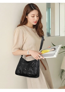 Détail du sac bandoulière en cuir noir lavé avec plusieurs poches et texture tressée