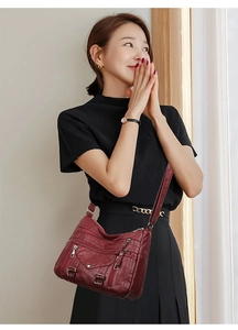 Detail view of burgundy leather crossbody bag with multiple pockets worn by model