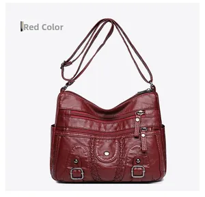 Détail du sac bandoulière bordeaux en cuir lavé montrant les poches zippées et la texture
