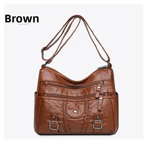 Détail du sac bandoulière en cuir marron avec plusieurs poches zippées et texture grainée