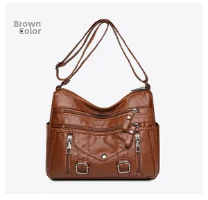 Detailed close-up of brown PU leather shoulder bag with multiple functional silver zippers