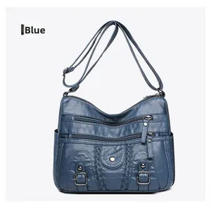 Détail du sac bandoulière bleu en cuir délavé avec plusieurs fermetures éclair et tresses