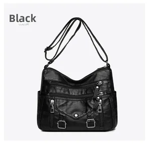 Macro detail of multi-pocket black crossbody bag showing soft leather texture and silver zippers