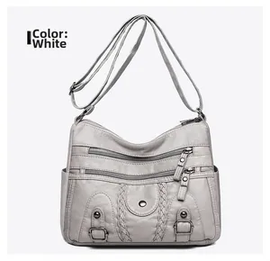 Gros plan du sac bandoulière multi-poches avec texture tissée et zips argentés