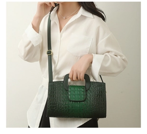 Detail der dunkelgrünen Handtasche mit Krokodilprägung und verstellbarem Riemen am Modell