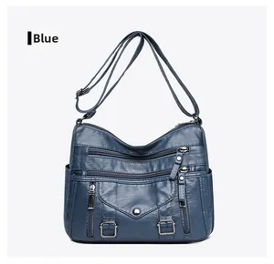 Detailed front view of blue crossbody bag featuring multiple zipper pockets and silver hardware