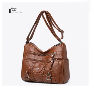 Détail du sac bandoulière en cuir lavé marron avec fermetures éclair et texture tressée