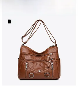Front detail of caramel brown leather crossbody bag with multiple zip pockets and compartments