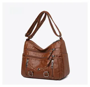 Detail view of brown multi-pocket crossbody bag with triple zippers and adjustable strap