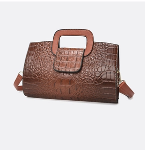 Detailansicht der Krokodilprägung und Metallschnalle an der braunen Damen-Handtasche