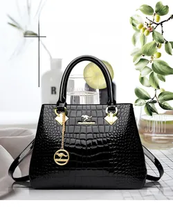 Detail of black crocodile texture handbag with gold hardware and kangaroo pendant
