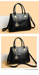 Detail of black crocodile-embossed patent leather bag with gold kangaroo emblem