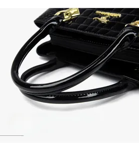 Close-up of black patent leather handbag featuring rectangular quilting and gold kangaroo logo