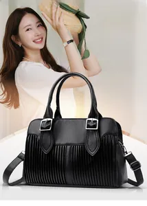 Detail of black leather handbag featuring accordion pleats and silver square buckle