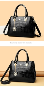 Detail of black crocodile embossed patent leather handbag with gold kangaroo logo and charms