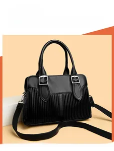 Detail of black pebbled leather tote featuring vertical pleats and silver metal buckles