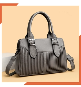 Close-up of grey leather handbag featuring pleated design and silver metal buckle detail