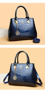Macro detail of dark blue crocodile embossed patent leather tote with brand charm