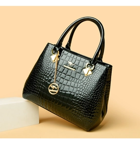 Detail of black faux crocodile skin texture and glossy finish on a designer handbag
