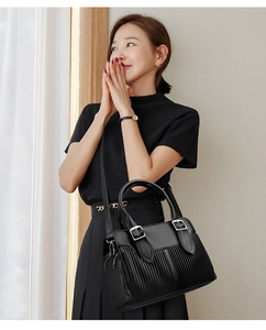 Close-up of black leather handbag featuring pleated texture and silver hardware details