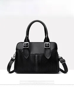 Close-up of black pebbled leather handbag featuring vertical pleats and silver buckle hardware