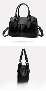 Detail view of black lychee leather handbag featuring silver buckles and pleated stitching