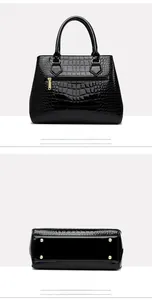 Detail view of black crocodile pattern handbag showing back zipper and protective metal feet