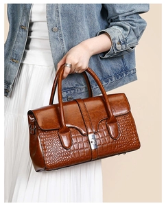 Détail du sac à main marron en cuir verni avec motif crocodile et fermoir métallique