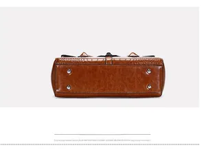 Vue détaillée du fond du sac en similicuir crocodile brillant avec quatre clous de protection