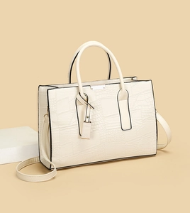 Close-up of cream white tote bag with embossed crocodile texture and geometric stitching
