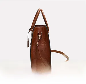 Side view of caramel crocodile pattern handbag showing detailed stitching and metal hooks