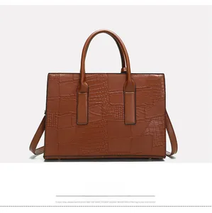 Detail view of the back of a caramel crocodile embossed tote bag with adjustable strap