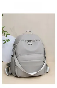 Close-up of gray pebble leather backpack with silver zippers and removable wide strap