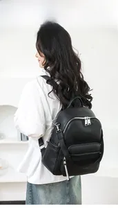 Elegant black lychee textured leather backpack worn by a model in a soft minimalist setting