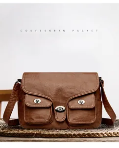Detail of dark brown vintage faux leather texture and metallic clasp closures on baguette bag