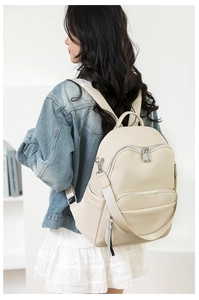Detail of a beige faux leather backpack with litchi texture and silver metallic zippers