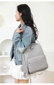 Side view of gray faux leather backpack with pebble grain texture and silver hardware