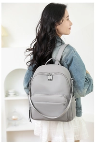 Side view of gray faux leather backpack with silver zippers worn by a model