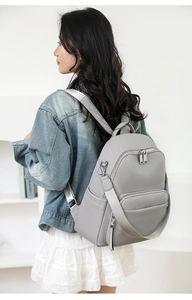Close-up of grey pebble leather backpack worn by a model in casual denim jacket
