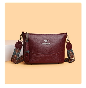 Detail der weinroten Eimertasche aus Litschi-Leder mit Känguru-Logo und Ethno-Gurt