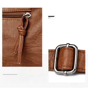 Close-up of brown pebbled leather texture with tassel zipper and silver buckle detail