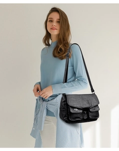 Detail of black faux leather bag texture and metal buckle on the front pockets