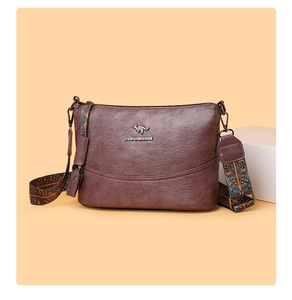 Details einer braunen Lederhandtasche mit Ethno-Gurt und geprägtem Metall-Logo