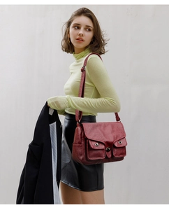 Detail of vintage red leather baguette bag featuring metal buckle and adjustable strap