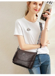 Detail der Vintage braunen Lederbeuteltasche mit buntem Schultergurt im Ethno-Muster