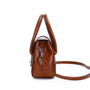 Sac à main en cuir verni marron avec doubles poignées et bandoulière réglable, vue de côté
